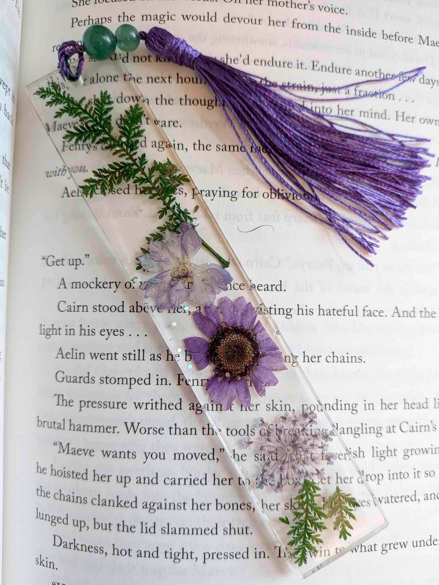Decorative bookmark with purple flower and tassel on an open book