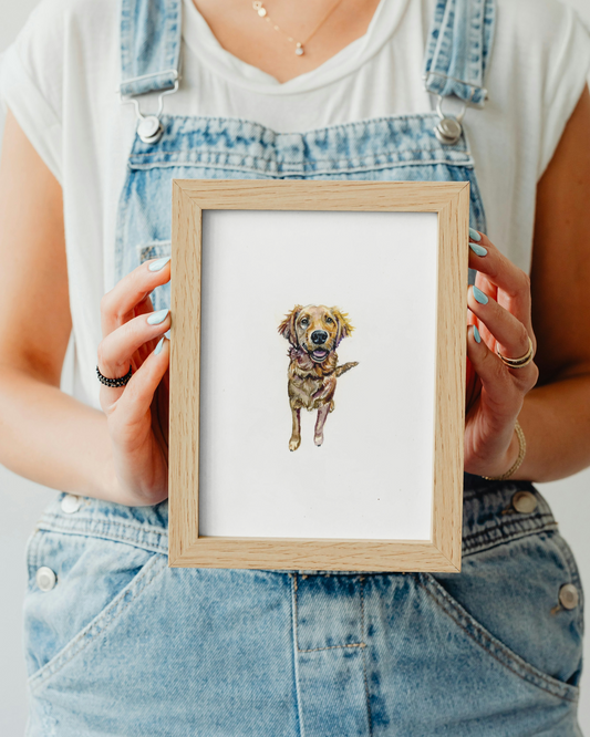 Person holding a framed picture of a dog with a plain background
