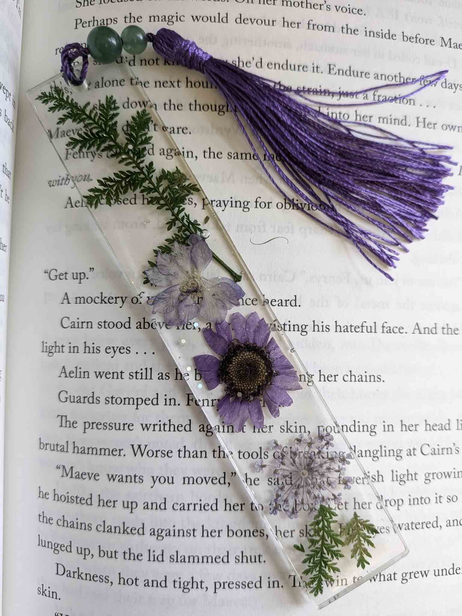 Decorative bookmark with purple flower and tassel on an open book