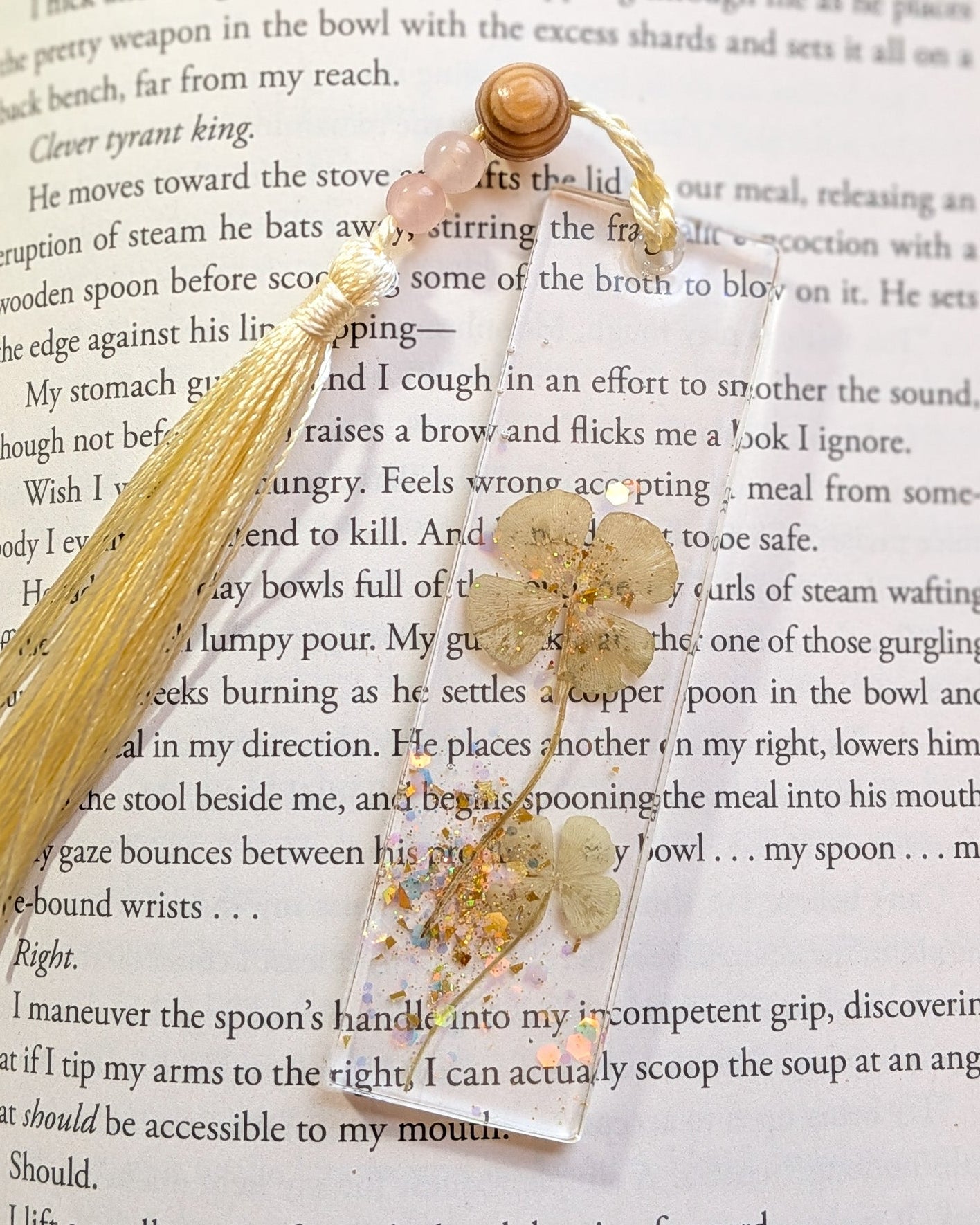 Decorative bookmark with gold tassel and floral elements on a book page